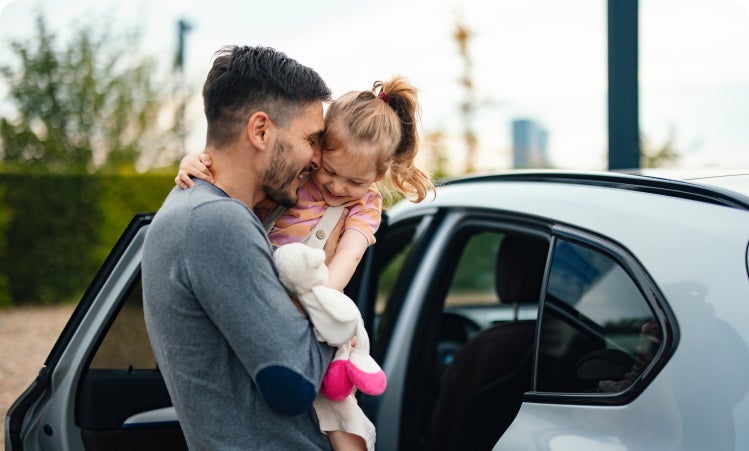 Father putting his daughter in their new car